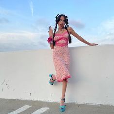 a woman in a pink dress leaning against a wall with her hand on the ground