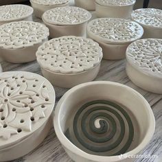 many white bowls with designs on them sitting on top of a wooden table next to each other