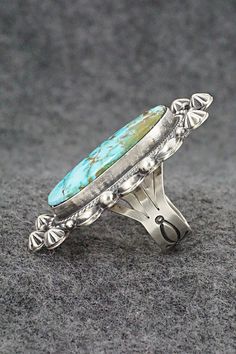 This beautiful Kingman turquoise and sterling silver ring was made by Navajo silversmith Tom Lewis. The back is signed and stamped sterling.Size: 7.5Length: 2"Width: 1 1/8"Free shipping on all orders! We ship with USPS and always include tracking. All orders ship within a day of payment.Returns are accepted up to 30 days after you receive your order. Just send us a message. Our shop offers cash back or store credit. The item must be returned in new condition. Southwestern Style Large Stone Turquoise Ring For Anniversary, Southwestern Style Large Turquoise Ring For Anniversary, Sterling Silver Turquoise Concho Ring, Western Sterling Silver Turquoise Ring With Patina, Untreated Southwestern Turquoise Ring For Anniversary, Unique Stamped Turquoise Ring, Untreated Silver Turquoise Ring In Southwestern Style, Southwestern Untreated Turquoise Sterling Silver Ring, Untreated Southwestern Turquoise Sterling Silver Ring