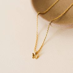 A gold mini butterfly charm set on a diamond cut chain. Tarnish Free - Long lasting protective coating safeguarding your jewelry from sweat, water, and more. 5x more gold that standard 18k gold plating over brass Hypoallergenic Lead Free Adjustable 16in to 18in Dainty Butterfly Necklace, Everyday Gold Butterfly-shaped Jewelry, Minimalist Gold Butterfly Necklace For Gift, Yellow Gold Butterfly Charm Necklace For Gift, Yellow Gold Butterfly Charm Necklace As Gift, Yellow Gold Charm Necklace With Butterfly For Gift, Yellow Gold Plated Butterfly Necklace Gift, Tiny Gold Plated Charm Necklaces, Tiny Gold-plated Charm Necklaces