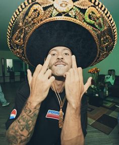 a man wearing a sombrero and holding his hands up to his face with both hands