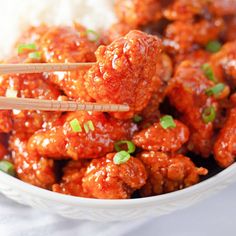 meatballs with chopsticks in a white bowl filled with rice and garnished with scallions