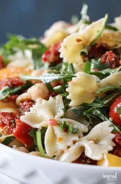 pasta salad with spinach and tomatoes in a white bowl