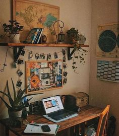 a laptop computer sitting on top of a wooden desk next to a potted plant