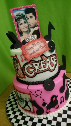 a cake that is decorated with pictures and music notes on the top, sitting on a checkered tablecloth