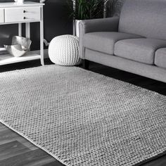 a living room with a gray couch and white rug on the floor in front of a grey wall