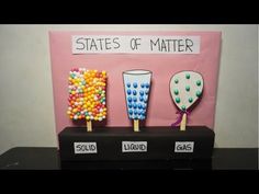 three different types of candy on sticks in front of a pink sign that says states of matter