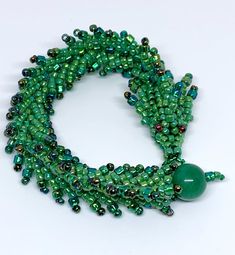 a green beaded necklace on a white surface