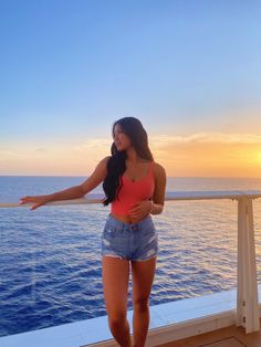 a woman standing on the deck of a boat looking at the ocean with her arms outstretched