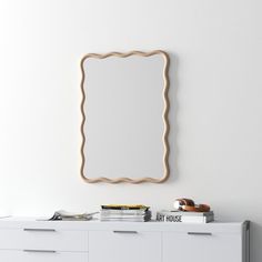 a white dresser with a mirror above it and some books on the sideboard next to it