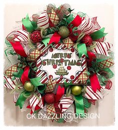 a christmas wreath with red and green decorations on the front door, hanging from a white wall