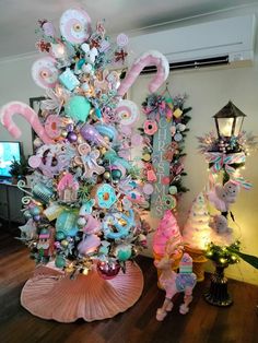 a decorated christmas tree with pink and blue ornaments on it's base, surrounded by other holiday decorations