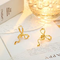 Who says everyday can't be charming? Gold Bow Earrings bring the coquette aesthetic with their classic ribbon design, meticulously designed with gleaming gold. Lightweight and comfortable, these high-quality earrings boast a smooth, shiny finish and long-lasting color. Effortlessly versatile, they pair perfectly with any outfit. Get ready to transform your everyday look from ordinary to oh-so-cute! DETAILS Plating: 18k Gold  Materials: 18k Gold on 925  Sterling Silver Size: 1.18"*0.98"(3.0cm*2.5 Elegant Gold Jewelry With Butterfly Knot, Gold Wedding Jewelry With Butterfly Knot Detail, Elegant Ribbon Jewelry For Anniversary, Gold Earrings With Decorative Bow As Gift, Elegant Jewelry With Decorative Bow For Anniversary, Elegant Gold Jewelry With Ribbon, Elegant Evening Jewelry With Butterfly Knot, Elegant Yellow Gold Jewelry With Ribbon, Chic Gold Earrings With Decorative Bow