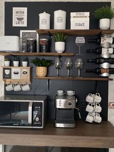 a coffee maker and some wine glasses on a shelf in a room with black walls