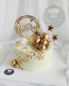 a white cake with gold decorations and a happy birthday sign