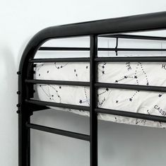 a black metal bunk bed with stars on the bottom and white sheets, against a white wall