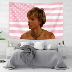 a young man in front of an american flag tapestry hanging on a wall above a bed