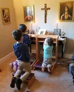 two children sitting on stools in front of a table with a crucifix