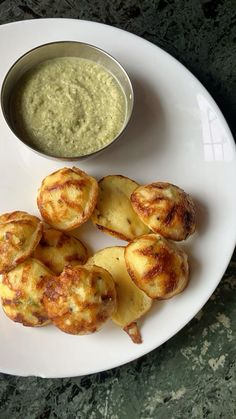 some food on a white plate with a bowl of dip