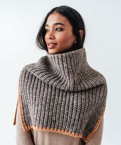 a woman wearing a gray and orange knitted shawl with an open cowl