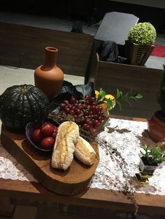 a table topped with fruits and vegetables on top of a wooden cutting board next to a vase