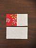 an open book sitting on top of a wooden table next to a red and white square