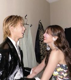 a man in a tuxedo is shaking the hand of a woman wearing a dress