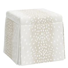 a white and beige stool with spots on the top, it has a square shaped footstool