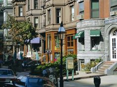 a city street filled with lots of tall buildings and cars parked on the side of it