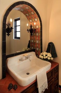 a white sink sitting under a mirror next to a wall mounted faucet in a bathroom