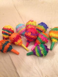 several colorful pinatas on a bed with white sheets