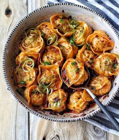 a bowl filled with dumplings on top of a wooden table next to a spoon