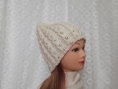 a doll wearing a white knitted hat with pearls