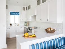 a kitchen with white cabinets and blue striped bench