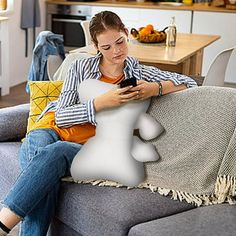 a woman sitting on a couch looking at her cell phone with an image of a person's head