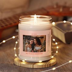 a candle with a photo on it sitting next to a string of lights and a guitar