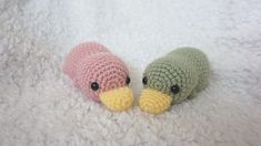 two crocheted stuffed birds laying on top of a white blanket next to each other