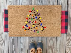 a person standing in front of a door mat with a christmas tree drawn on it