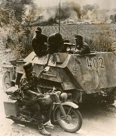 an old black and white photo of men riding on a motorcycle next to a tank