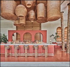 the bar is surrounded by wicker hanging from the ceiling and wooden stools in front of it