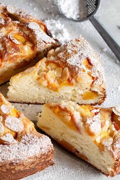 a cake that has been cut into pieces and is sitting on a table next to a scoop of powdered sugar