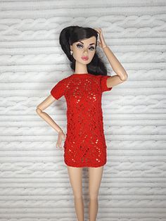 a doll is posed in a red dress and shoes with her hand on her head