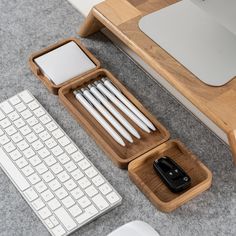 a desk with a keyboard, mouse and cell phone holder on the floor next to it