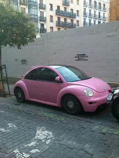 a pink car parked next to a motorcycle