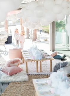 two girls are standing in the background behind a table with balloons on it and other decorations