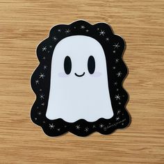 a sticker with a ghost on it sitting on a wooden surface in front of a wood table