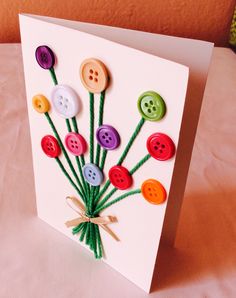 a card with buttons on it sitting on top of a white table next to a pink wall