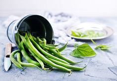 some green beans are in a bucket and on the table next to a knife - stock photo - images