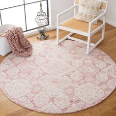 a white chair sitting on top of a wooden floor next to a pink and white rug