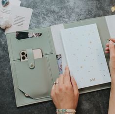 a woman is holding an open notebook and taking notes from her planner while sitting on the floor